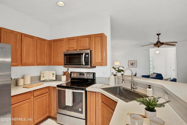 kitchen featuring a sink, a ceiling fan, light countertops, appliances with stainless steel finishes, and brown cabinets