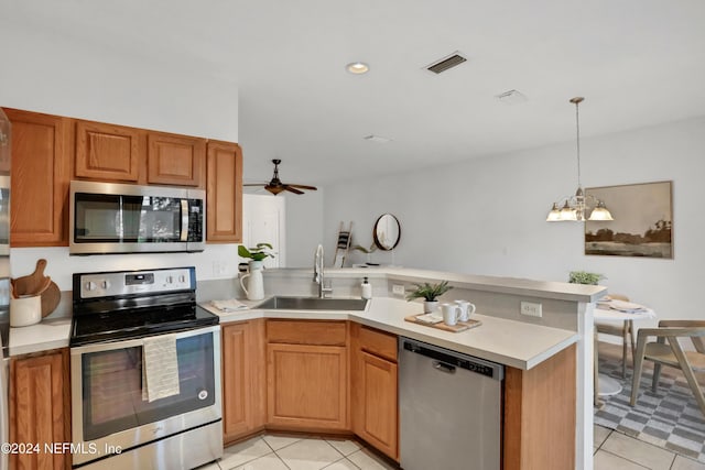 kitchen with a peninsula, appliances with stainless steel finishes, a sink, and light countertops