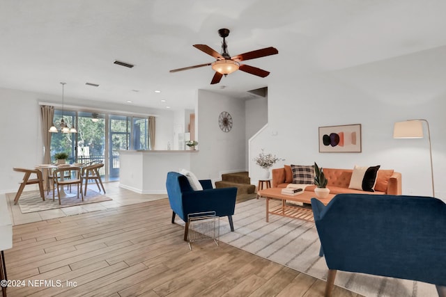 living area featuring visible vents, baseboards, ceiling fan with notable chandelier, light wood-style floors, and recessed lighting