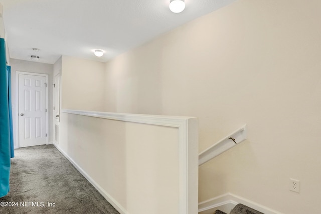 hallway featuring carpet flooring, an upstairs landing, and baseboards