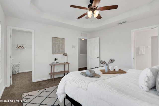 bedroom featuring visible vents, baseboards, a spacious closet, a tray ceiling, and carpet floors