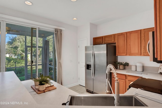 kitchen with recessed lighting, light countertops, appliances with stainless steel finishes, light tile patterned flooring, and a sink