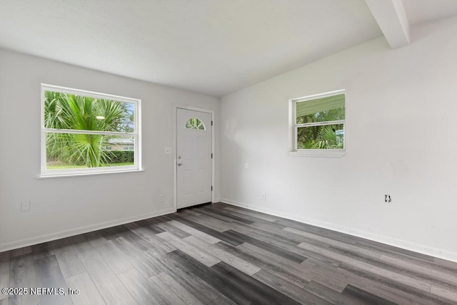 spare room featuring beamed ceiling, plenty of natural light, wood finished floors, and baseboards