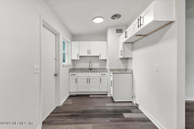 kitchen featuring a sink, visible vents, baseboards, white cabinets, and dark wood finished floors