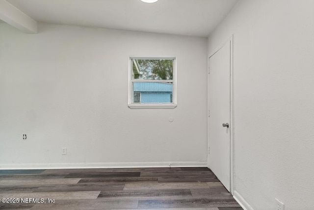 empty room with lofted ceiling, baseboards, and dark wood-style flooring