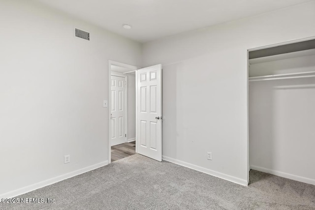 unfurnished bedroom with carpet, visible vents, baseboards, and a closet