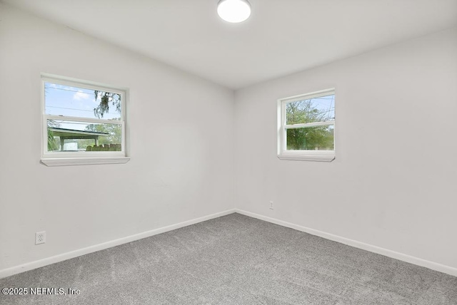 carpeted empty room featuring baseboards