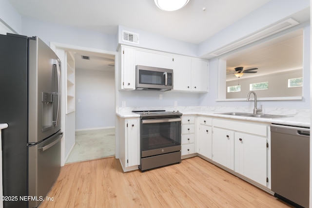 kitchen featuring a sink, visible vents, white cabinetry, appliances with stainless steel finishes, and light wood-type flooring