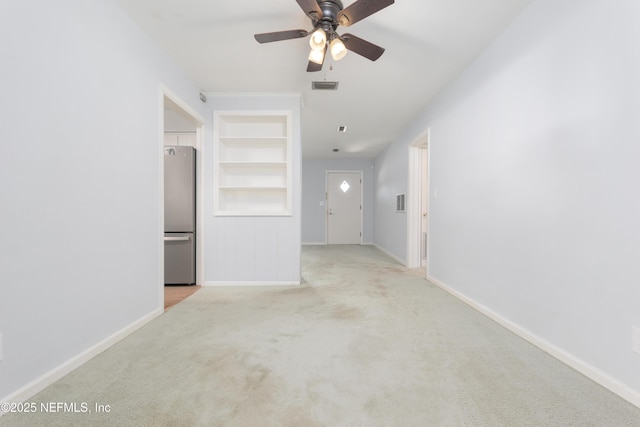 empty room featuring built in shelves, carpet, visible vents, and baseboards