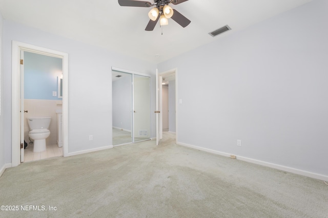 unfurnished bedroom featuring carpet, tile walls, a closet, visible vents, and ensuite bath