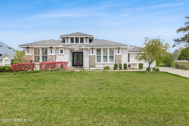 prairie-style home featuring a garage, a front yard, concrete driveway, and stone siding