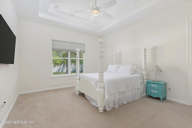 bedroom with baseboards, a tray ceiling, a ceiling fan, and light colored carpet