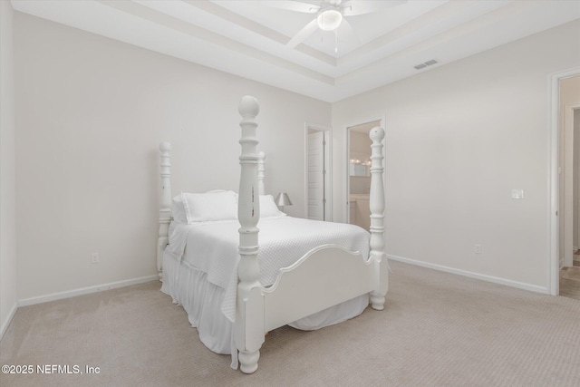 carpeted bedroom with baseboards, visible vents, a raised ceiling, ceiling fan, and ensuite bathroom