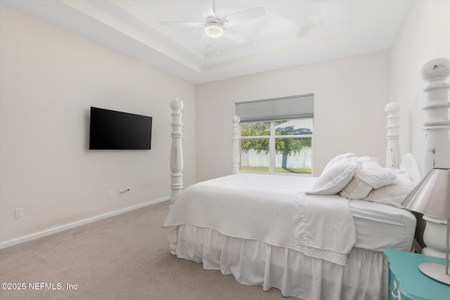 bedroom featuring ceiling fan, a tray ceiling, carpet, and baseboards