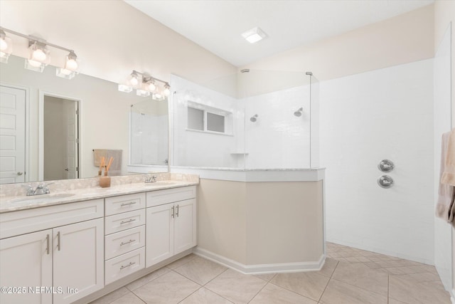 bathroom featuring tile patterned flooring, double vanity, a sink, and a walk in shower