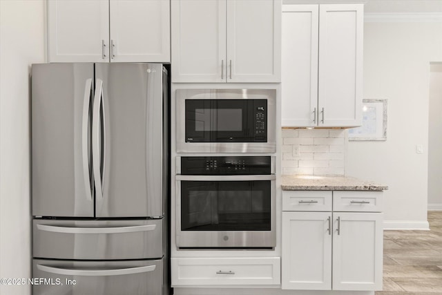 kitchen featuring white cabinets, decorative backsplash, appliances with stainless steel finishes, light stone counters, and crown molding