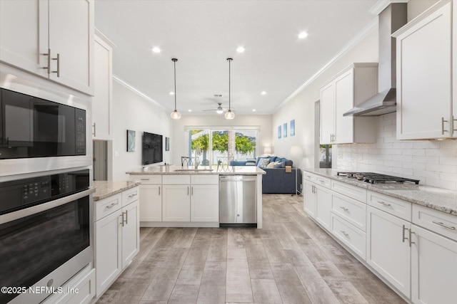 kitchen with tasteful backsplash, light wood-style flooring, open floor plan, stainless steel appliances, and wall chimney range hood