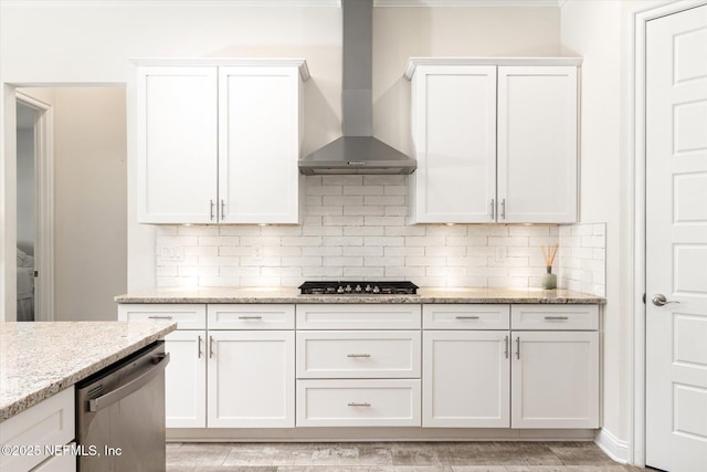 kitchen featuring white cabinets, decorative backsplash, wall chimney exhaust hood, light stone counters, and stainless steel appliances