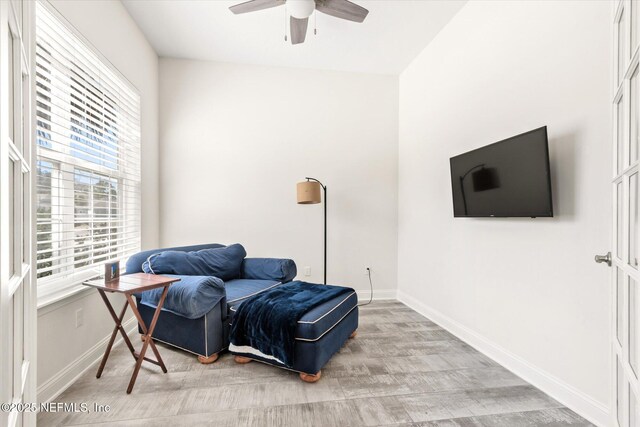 living area featuring a ceiling fan, light wood-type flooring, and baseboards