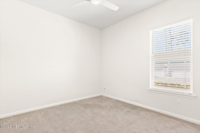 empty room featuring ceiling fan, baseboards, and light colored carpet