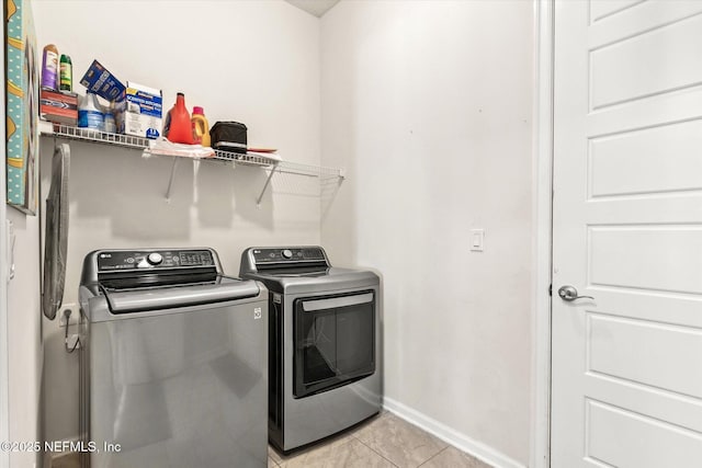 clothes washing area with laundry area, light tile patterned floors, baseboards, and separate washer and dryer