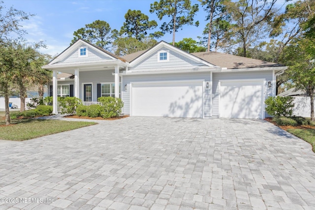 view of front of home with a garage, decorative driveway, and a porch