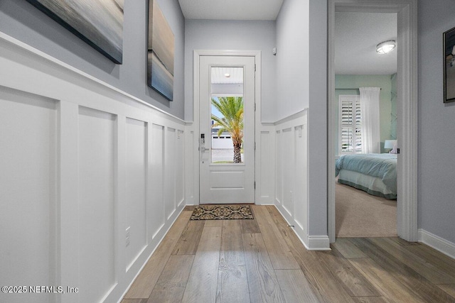 entryway featuring wainscoting, a decorative wall, and wood finished floors