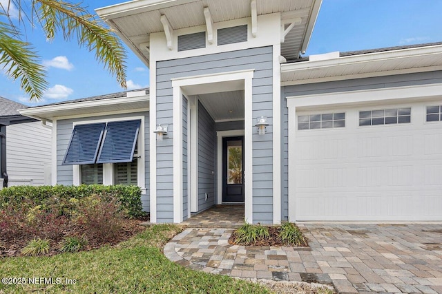 doorway to property featuring a garage and decorative driveway