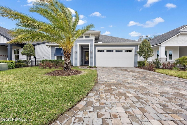 view of front of home with a front lawn, decorative driveway, fence, and an attached garage