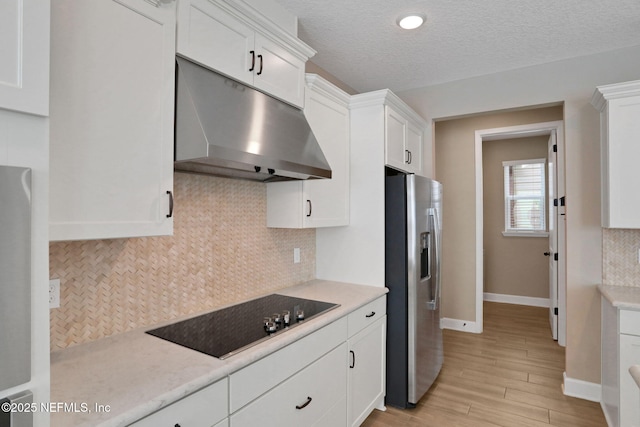 kitchen featuring black electric cooktop, light countertops, under cabinet range hood, white cabinetry, and stainless steel refrigerator with ice dispenser