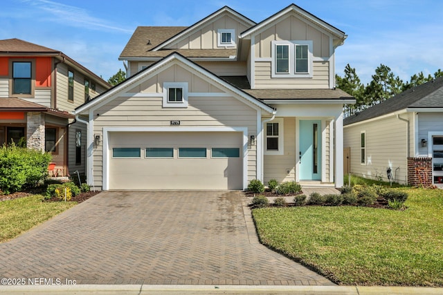 craftsman inspired home with a garage, decorative driveway, a front lawn, and board and batten siding