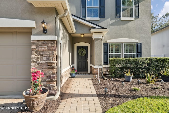 entrance to property featuring stone siding, an attached garage, and stucco siding