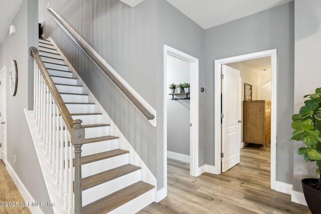 stairs with wood finished floors and baseboards