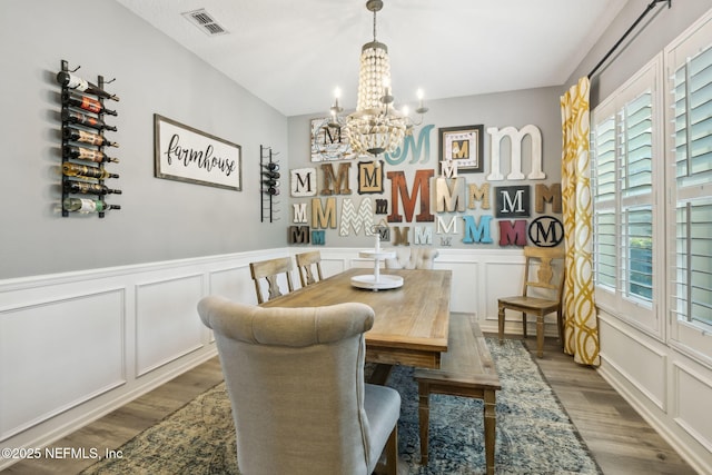 dining space featuring visible vents, wood finished floors, a wealth of natural light, and a decorative wall