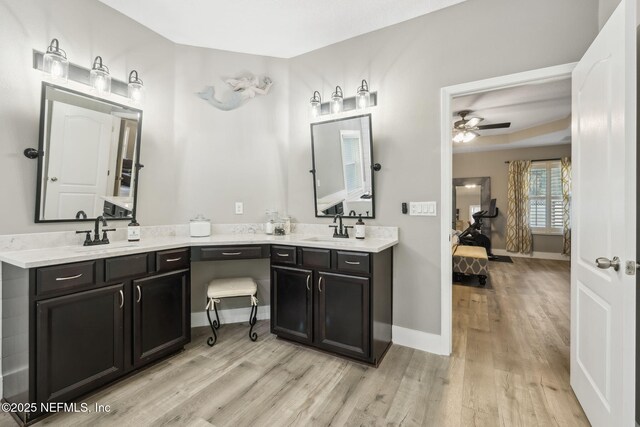 bathroom featuring wood finished floors, a sink, baseboards, and ensuite bathroom