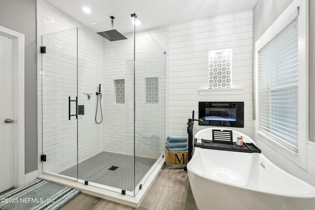 full bath with a stall shower, a soaking tub, and wood finished floors