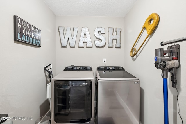 washroom with laundry area, a textured ceiling, and washing machine and clothes dryer