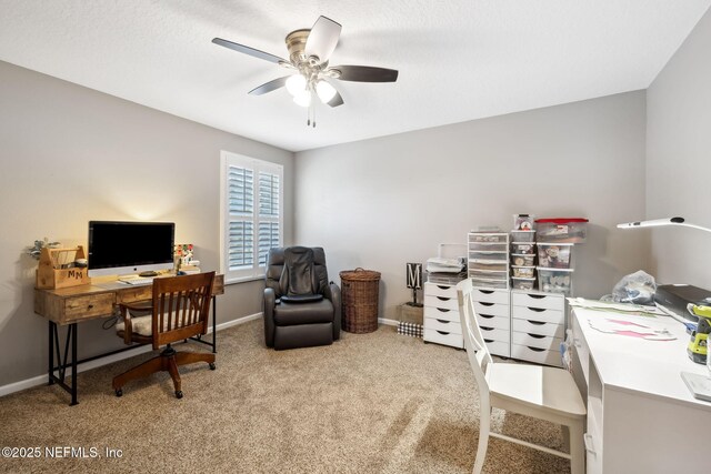 carpeted office with a ceiling fan and baseboards