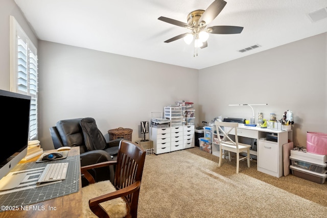 carpeted home office with ceiling fan and visible vents