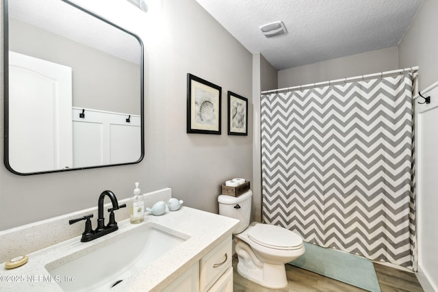 bathroom with a textured ceiling, toilet, a shower with shower curtain, wood finished floors, and vanity