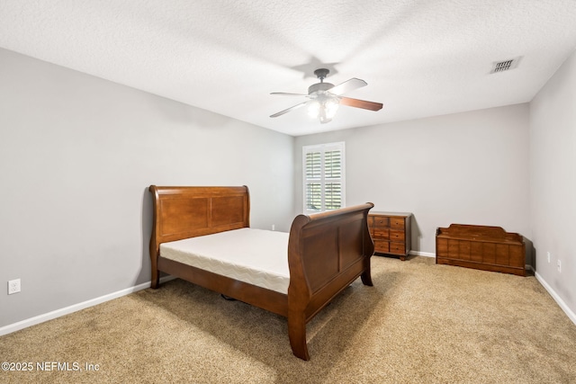 carpeted bedroom featuring a textured ceiling, a ceiling fan, visible vents, and baseboards