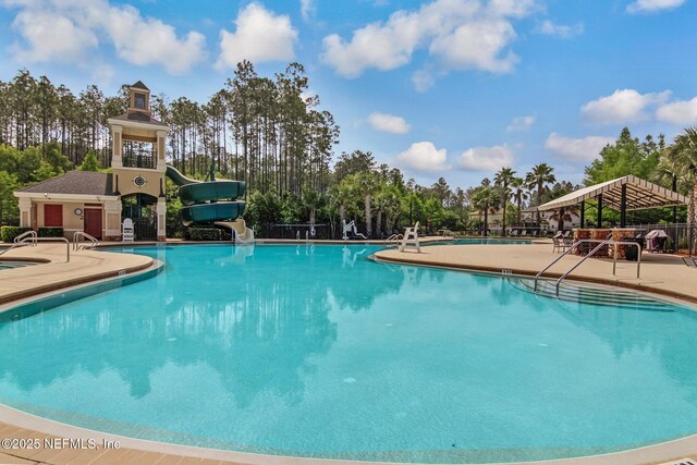 pool with a water slide, a patio area, and fence