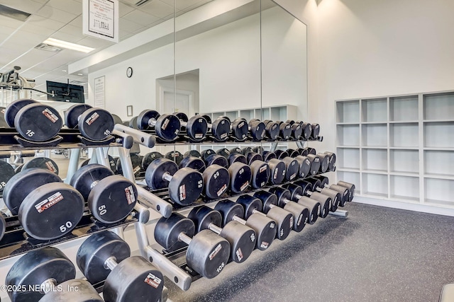 workout area with a drop ceiling and a towering ceiling