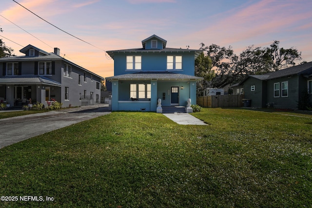 american foursquare style home featuring stucco siding, a yard, and fence