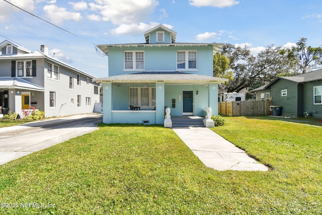 traditional style home featuring covered porch, a front lawn, fence, and stucco siding