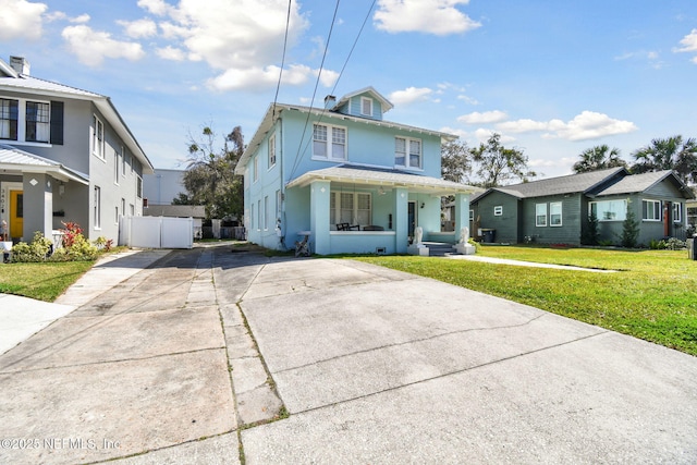 american foursquare style home with covered porch, fence, concrete driveway, stucco siding, and a front yard