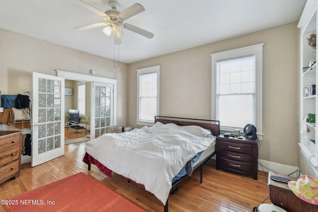 bedroom featuring french doors, wood finished floors, a ceiling fan, and baseboards