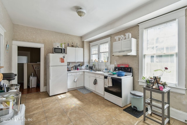 kitchen with under cabinet range hood, white appliances, a sink, white cabinetry, and light countertops