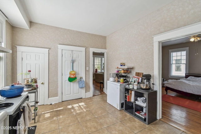 kitchen featuring electric stove, wallpapered walls, baseboards, and light tile patterned floors