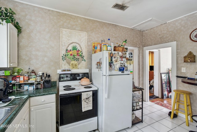 kitchen featuring light tile patterned floors, white appliances, visible vents, white cabinets, and dark countertops